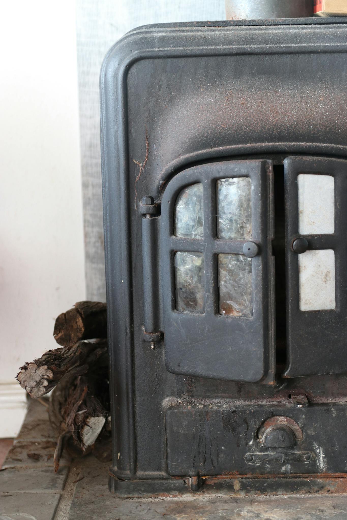 An old iron fireplace with stacked wood, perfect for cozy winter settings.