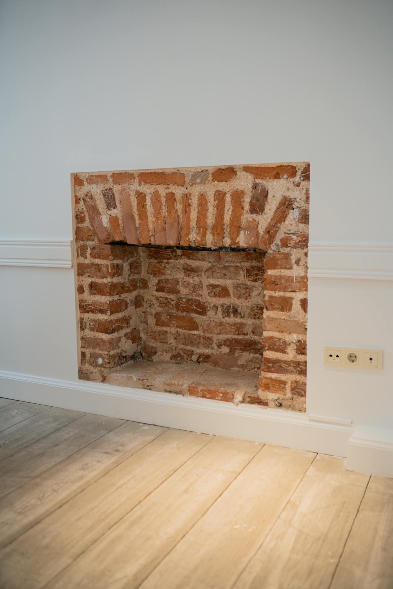 Inviting living room featuring a redbrick fireplace and wooden floor for a warm ambiance.